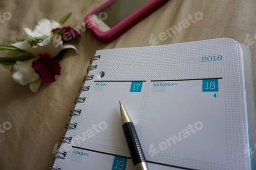 Preview: 2018 weekly calendar planner on bed with phone and flower