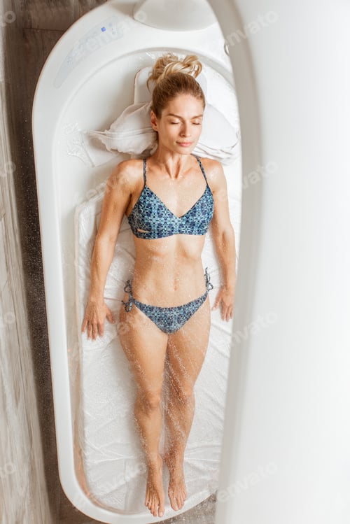 Preview: Woman lying under the hot shower in the spa