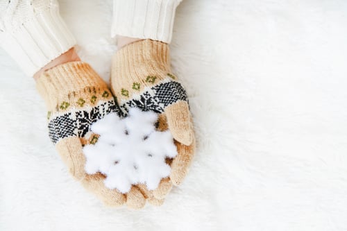 Hands in Mittens Hold White Snowflake