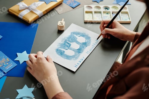 Preview: Hands of young creative woman with paintbrush working over new postcard
