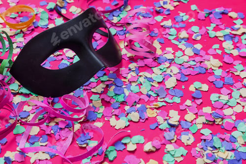 Preview: Carnival confetti festive background. Black mask and colorful bright paper circles on pink.