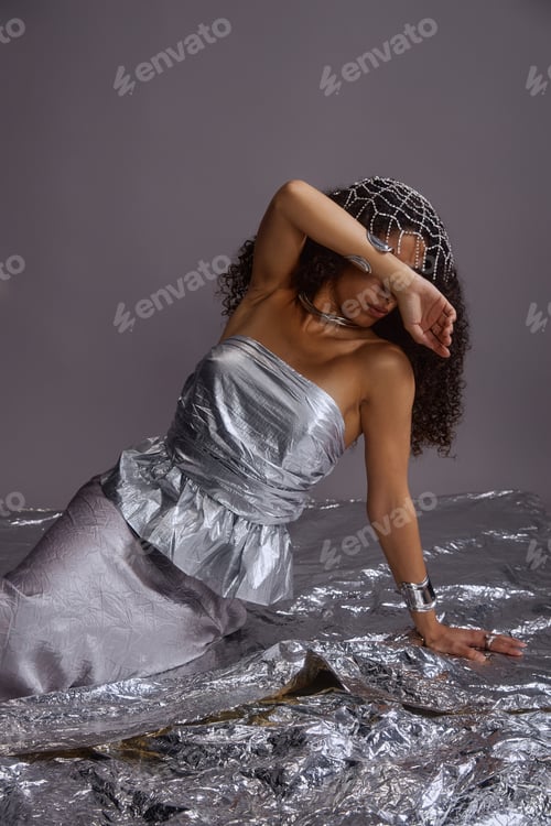 Preview: Young Woman Leaning on Elbow Draped in Metallic Fabric Studio