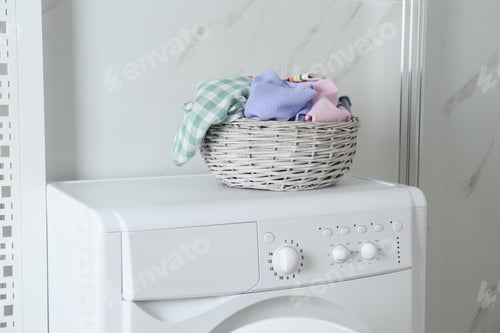 Vista previa: Wicker laundry basket with different clothes on washing machine in bathroom