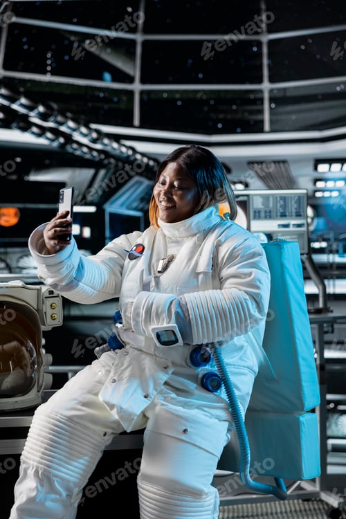 Preview: Female astronaut scientist talking selfies using phone in spaceship