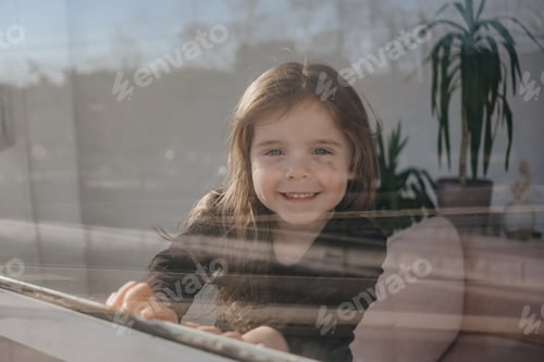 Preview: beautiful little girl looking through a window