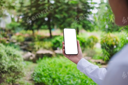 Visualização: Imagem de maquete de uma mulher segurando um telefone celular com tela de desktop branca em branco na natureza ao ar livre