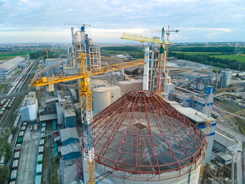Preview: Aerial view of cement factory under construction with high concrete plant structure and tower cranes