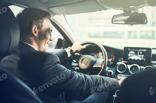 Preview: Smiling young businessman changing music stations while driving