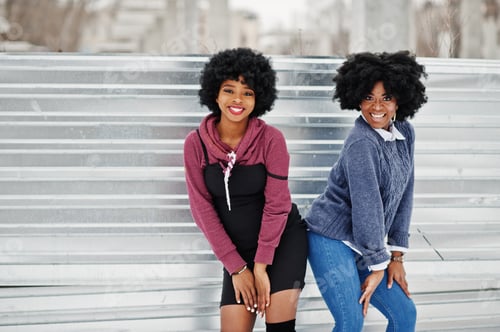 Preview: Two curly hair african american woman wear on sweaters posed at winter day.