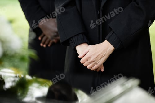 Preview: Close up of person in black standing by coffin