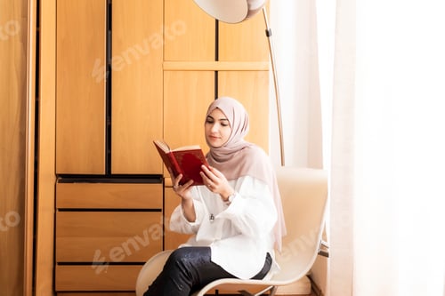 Young woman enjoying a book in a cozy room corner.