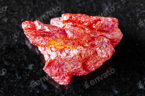Preview: sample of rough realgar mineral on black granite