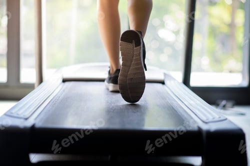 Preview: Close up of woman legs with runner shoes is jogging on running machine or treadmill in fitness gym