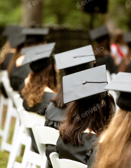 Preview: A group of students sit at a graduation ceremony, focus on mortarboard hat.