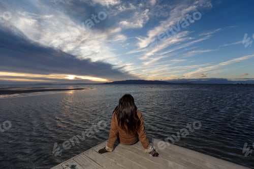 Preview: Young woman looking out from pier at sunset, Tarragona, Catalonia, Spain