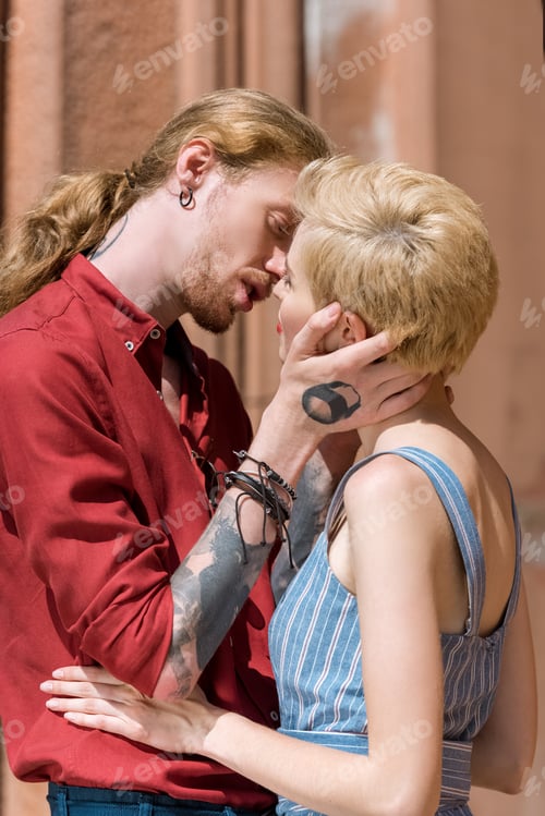 Preview: tattooed boyfriend and stylish girlfriend going to kiss on street