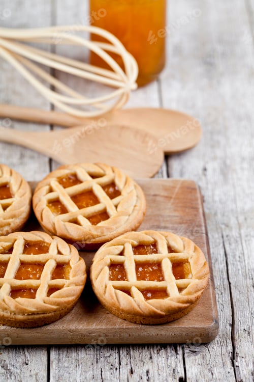 Preview: Fresh baked tarts with marmalade or apricot jam filling and on cutting board.