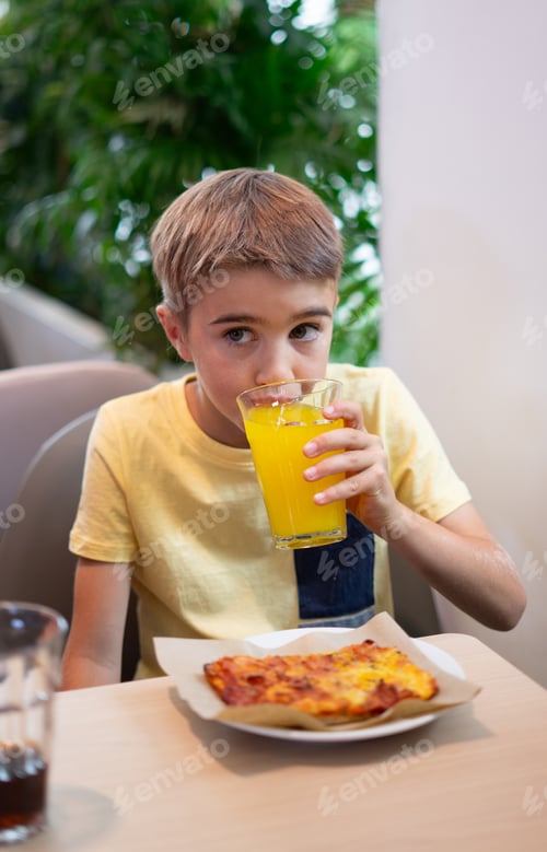 Preview: Boy drinking a soft drink and eating pizza in a restaurant