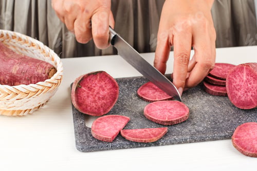Preview: Woman Slice Cut Japanese Purple Sweet Potato with Knife in the Kitchen