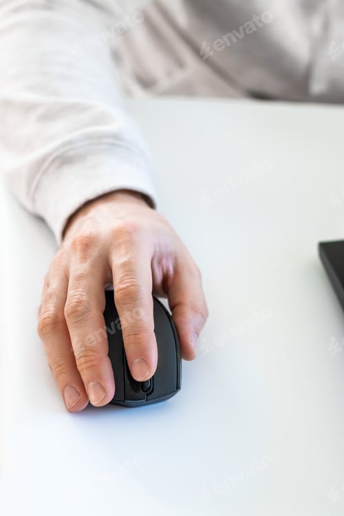 Preview: A male hand holding a computer mouse to work on a laptop in the light room at home