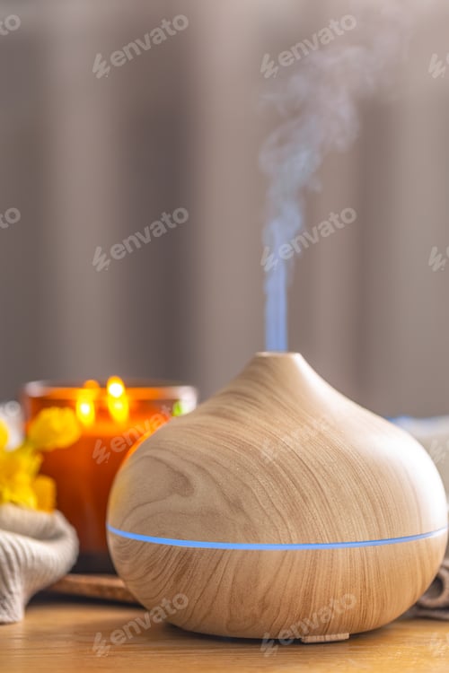Preview: Wood aroma diffuser producing mist with candle and flowers in cozy spa interior. Wellness diffuser.