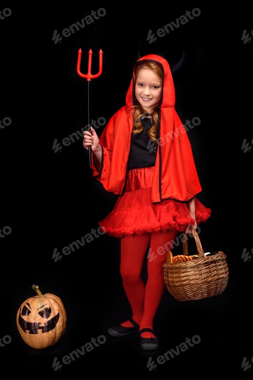 Preview: child in halloween costume of devil with pitchfork, jack o lantern and sweets in basket, isolated on