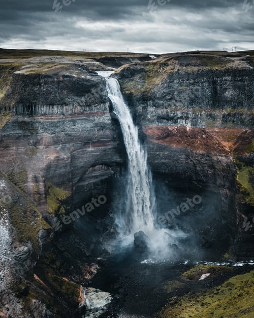 Preview: Breathtaking view of a powerful waterfall surrounded by rocky cliffs in Iceland