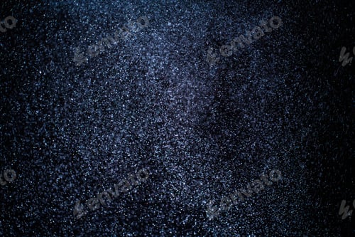 Preview: Organic dust particles floating on a colorful light beam on black background.