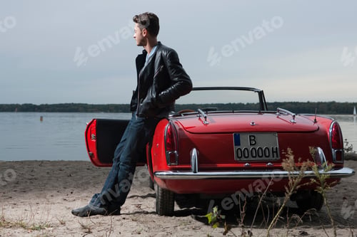 Preview: Germany, Berlin, Lake Wannsee, Young man standing by car, looking over water, portrait