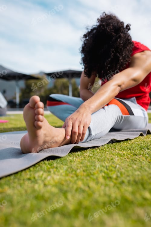 Preview: Biracial man practicing yoga and stretching in garden