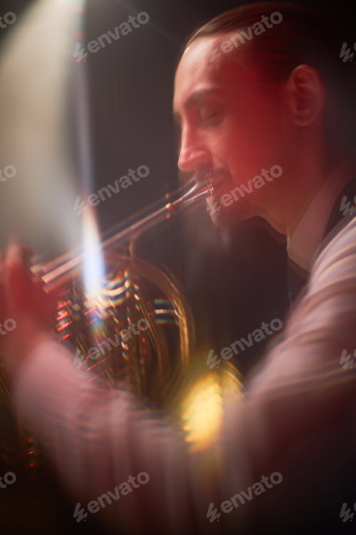Preview: Male Musician Enjoying Playing French Horn on Stage under Red Neon Light