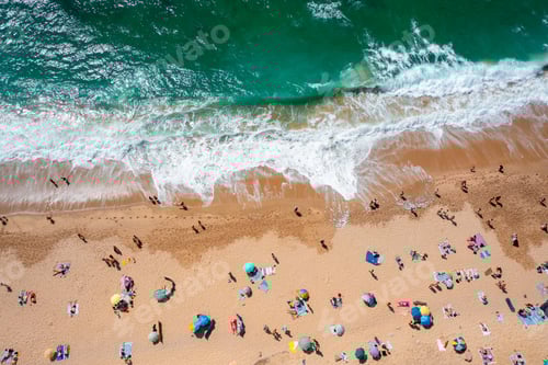 Visualização: Visão aérea de drone de turistas anônimos e guarda-sóis na costa arenosa