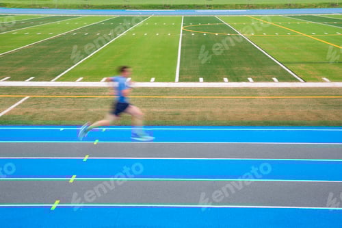 Preview: Side view of man running on blue track on sports field, motion blur.