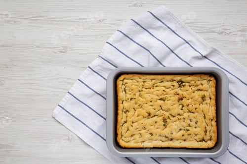 Preview: Home-baked Rosemary Garlic Focaccia Bread on baking tray, top view.