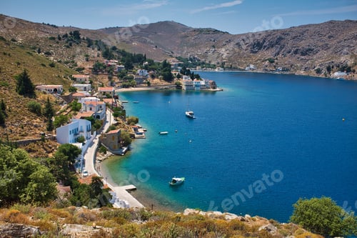 Preview: High angle shot of a beautiful sea surrounded by high rocky mountains and buildings in Symi, Greece