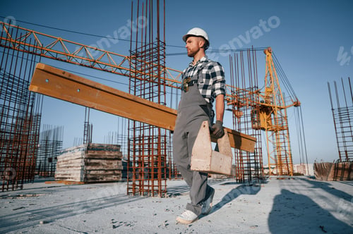Preview: With toolbox and wooden plank. Man is working on the construction site at daytime
