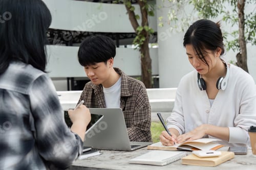 Preview: Group of happy students checking results on laptop and tablet while sitting on college campus