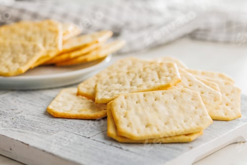 Preview: Golden Baked Crackers on cutting board on a White kitchen table.