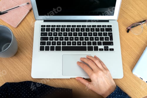 Preview: Top view of woman using laptop in office. Phone, notebook and eyeglasses.