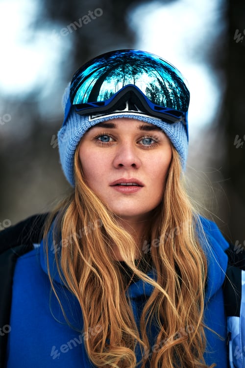 Preview: Beautiful young girl in a blue ski suit and helmet. On the head are glasses for snowboarding. Snow