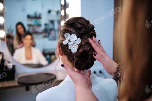 Preview: Stylist finishing a stylish hairstyle for a bride at the hair salon.