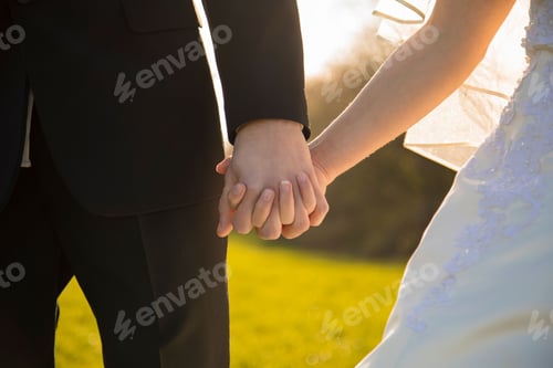Preview: Closeup of a young couple holding hands at their wedding.