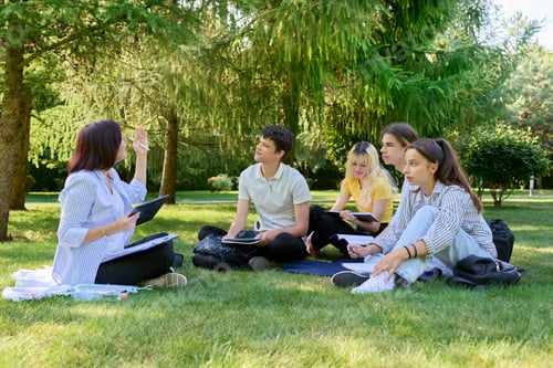 Preview: Outdoor, group of students with female teacher sitting on grass