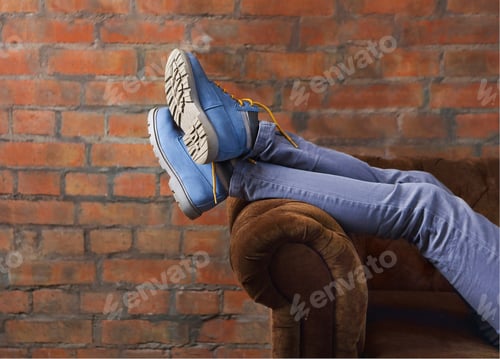 Preview: Half body of a female, posing her jeans and boots on a sofa