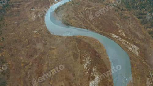 Preview: Nature from the height of a drone. Clip. The blue clear winding river next to the gray forest flows