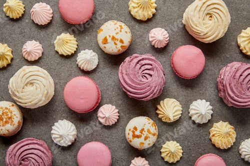 Preview: Top view of assorted pink white and yellow macaroons with meringues on gray background