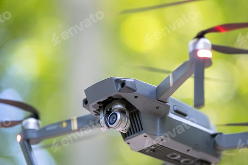 Preview: Drone aircraft with blurred fast rotating propellers and photo camera flying in air
