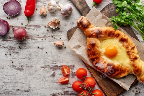 Preview: Adjarian khachapuri with vegetables, spices and cilantro on table