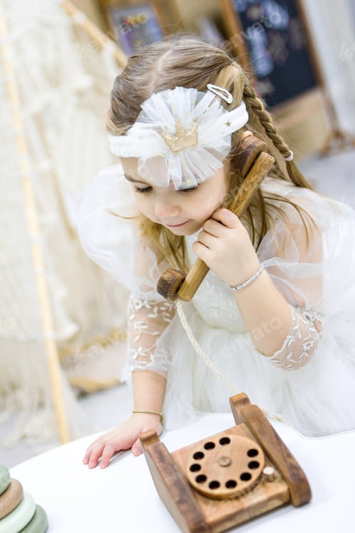 Preview: Girl Playing with a Wooden Toy Telephone Indoors