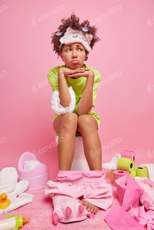Preview: Vertical shot of displeased dark skinned ethnic woman with cury hair keeps hands under chin has unha
